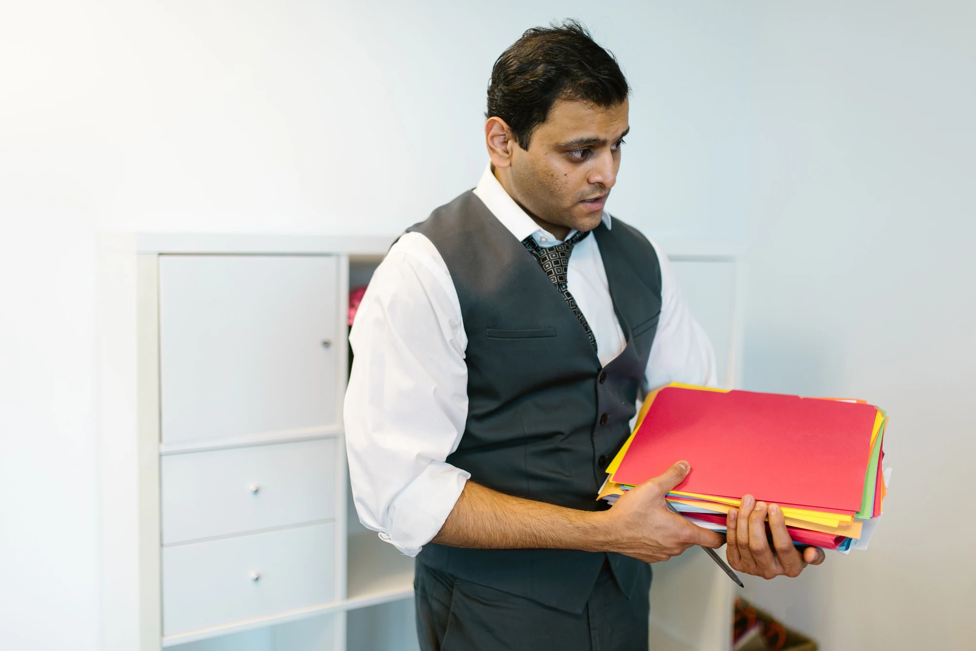 Man carrying a stack of document folders in an office