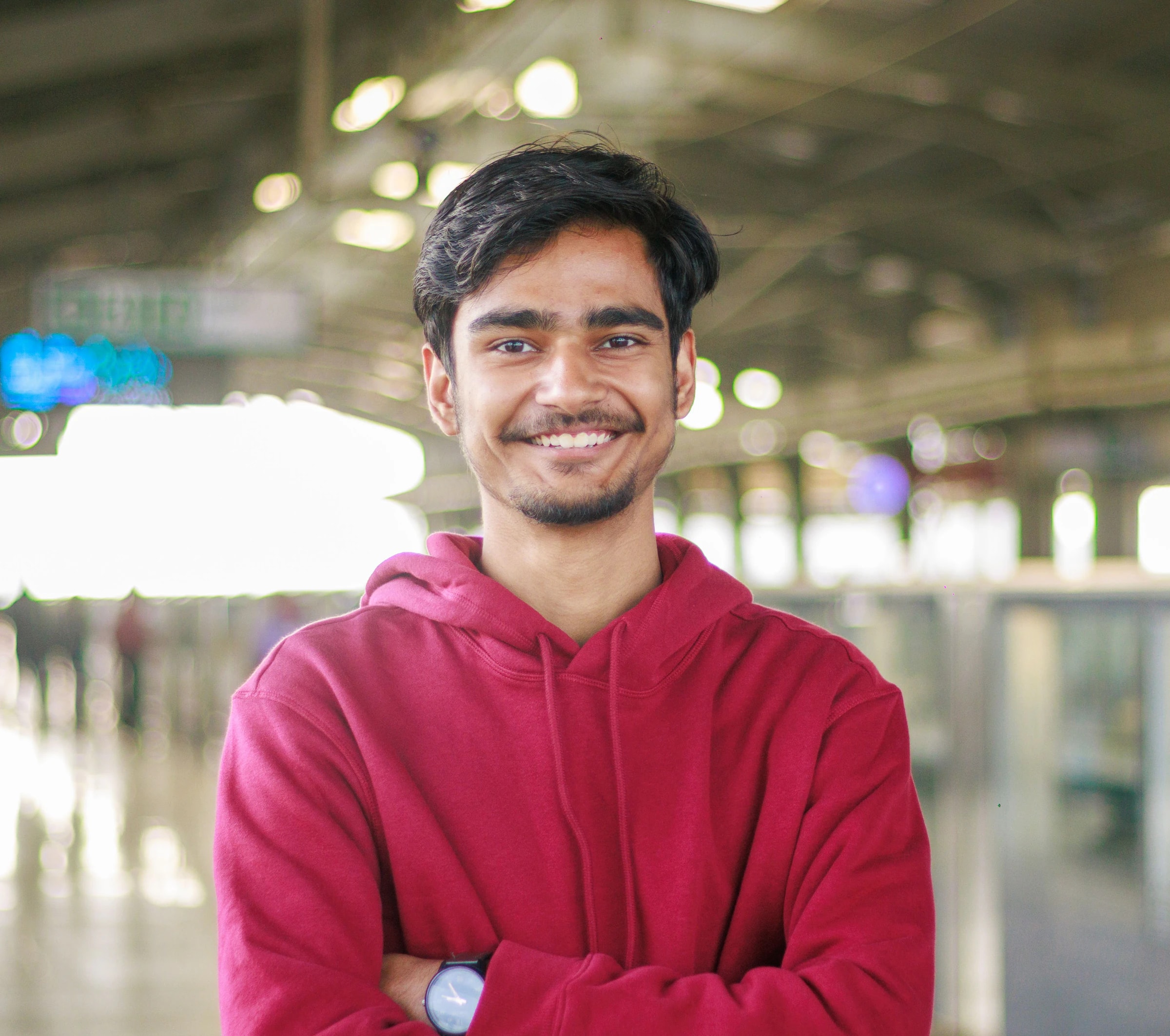 Smiling young man with arms folded at a metro station